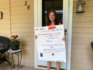 Student Josie holding sign she made for Food Drive Campaign